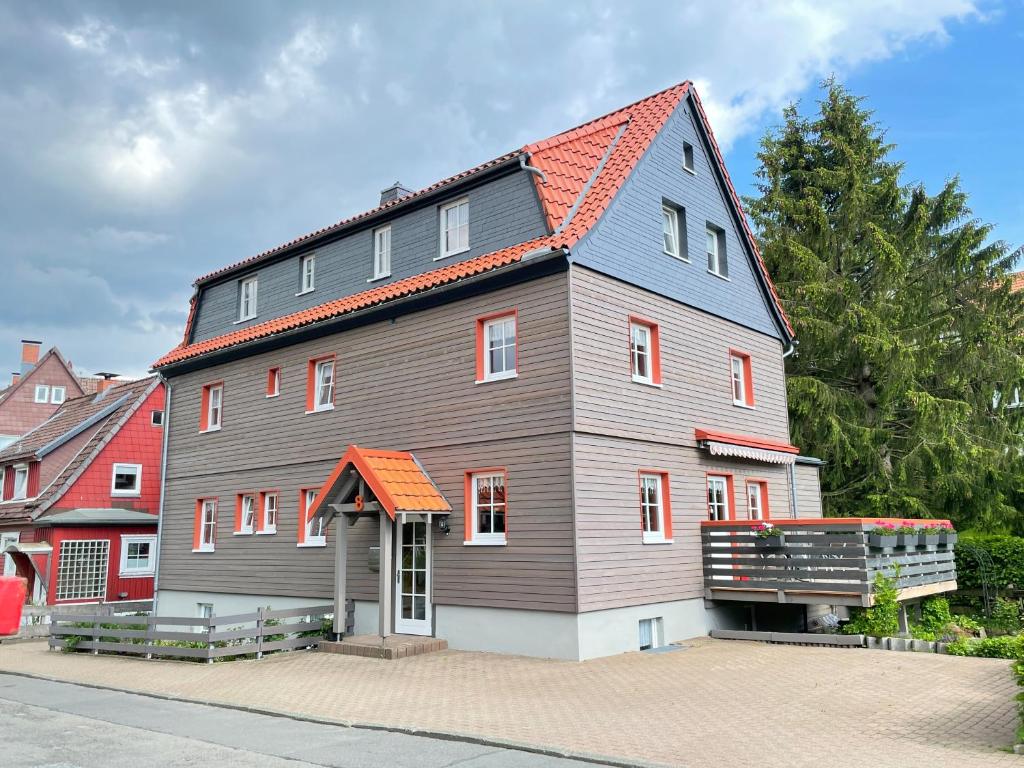 une grande maison grise avec un toit orange dans l'établissement Landhaus Wiesengrund, à Braunlage