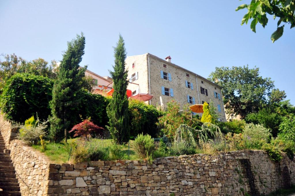 a garden in front of a building with a stone wall at Ruine-Motovun DH in Motovun