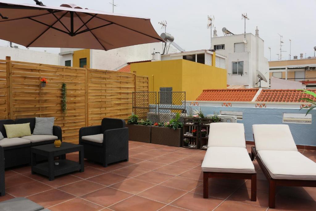 une terrasse avec des chaises, des tables et un parasol dans l'établissement Home Sweet Home VRSA, à Vila Real de Santo António