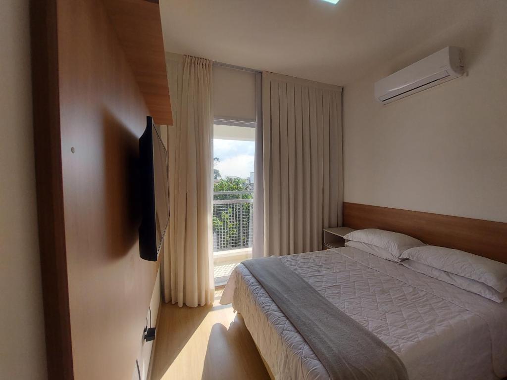 a bedroom with a bed and a large window at Flat Completo in Cotia