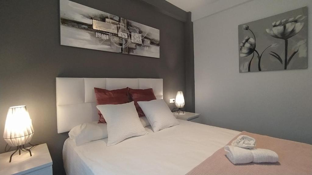 a bedroom with a large white bed with two lamps at BEACH&GARDEN in Málaga