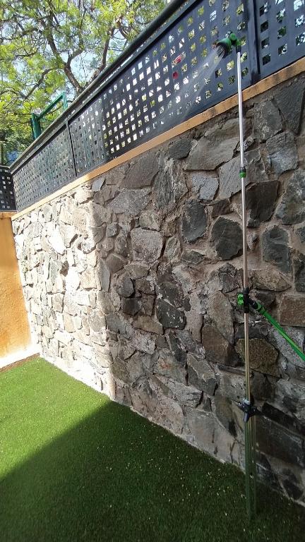 a stone wall with a fence and a green lawn at BEACH&GARDEN in Málaga