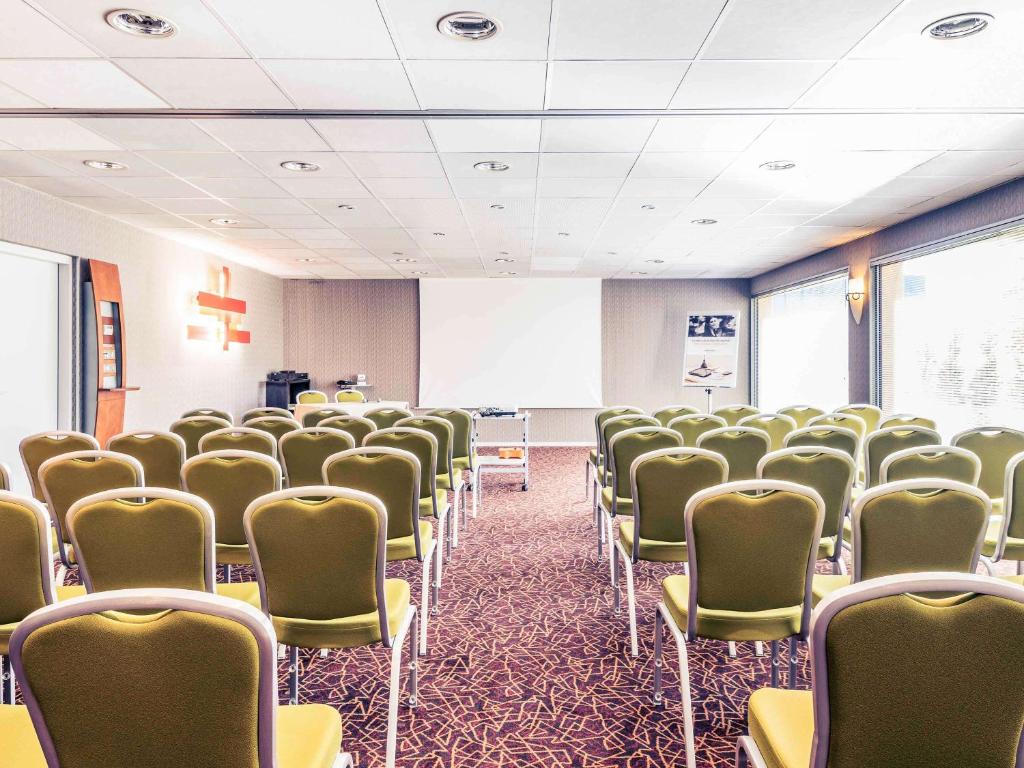 an empty room with chairs and a white screen at Mercure Bourg En Bresse in Bourg-en-Bresse