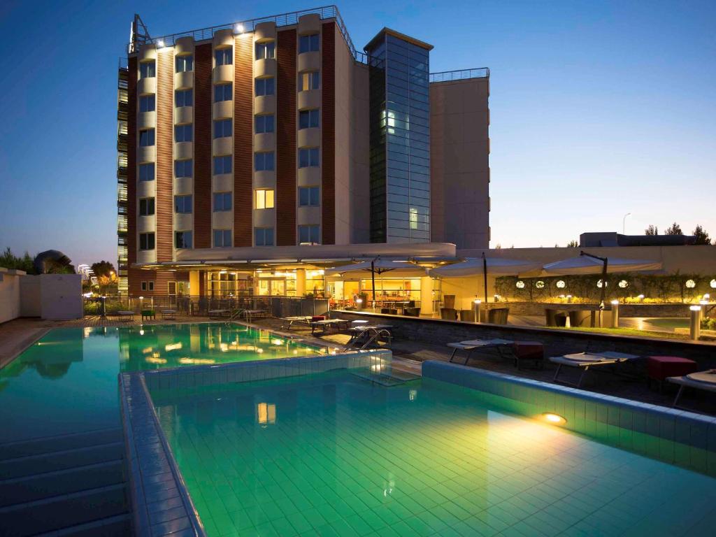 a large swimming pool in front of a hotel at Novotel Salerno Est Arechi in Salerno