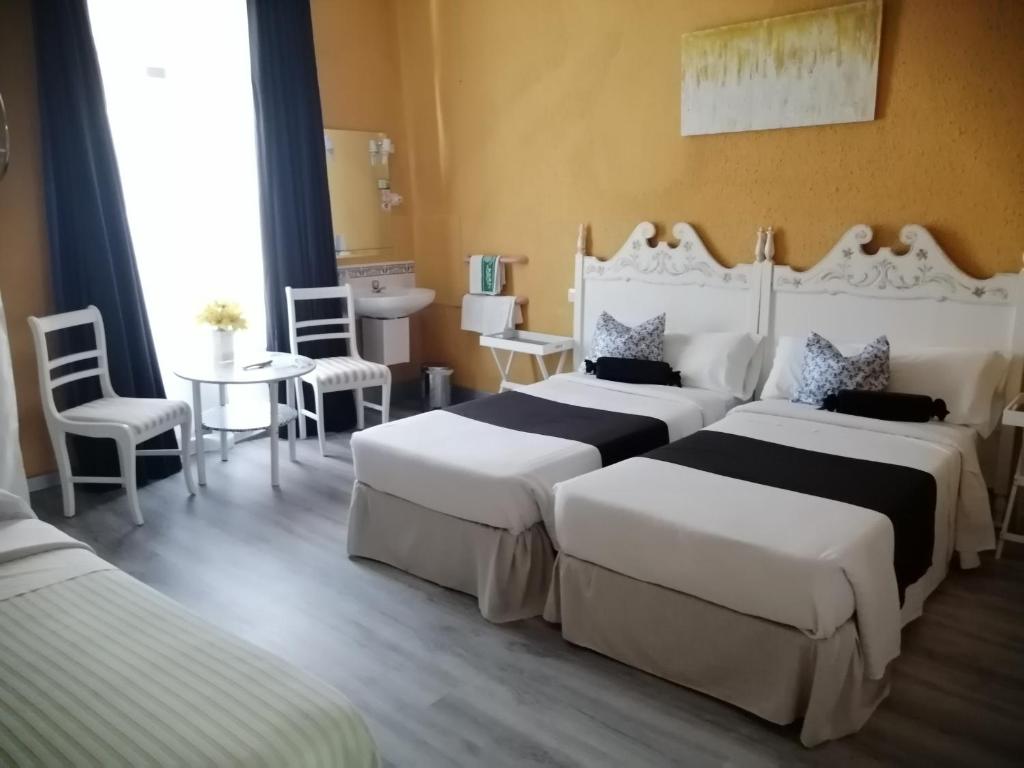 a hotel room with two beds and a table and chairs at Hospedaje Botin in Santander