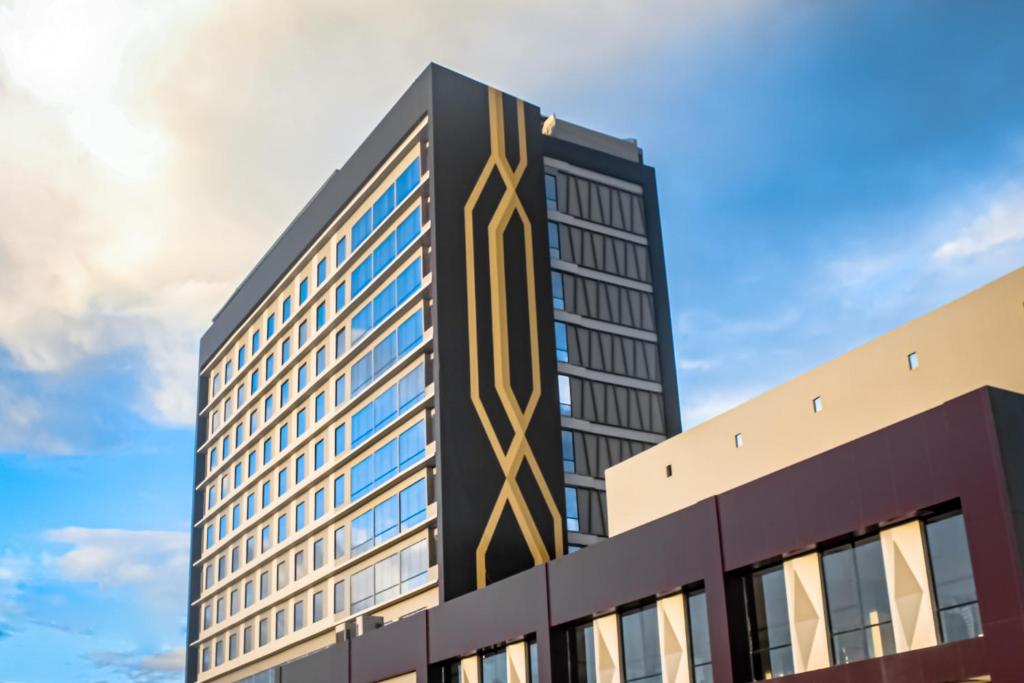 Tobadi的住宿－Suni Hotel and Convention Abepura managed by Parkside，一座高大的黑色建筑,上面设计着黄色