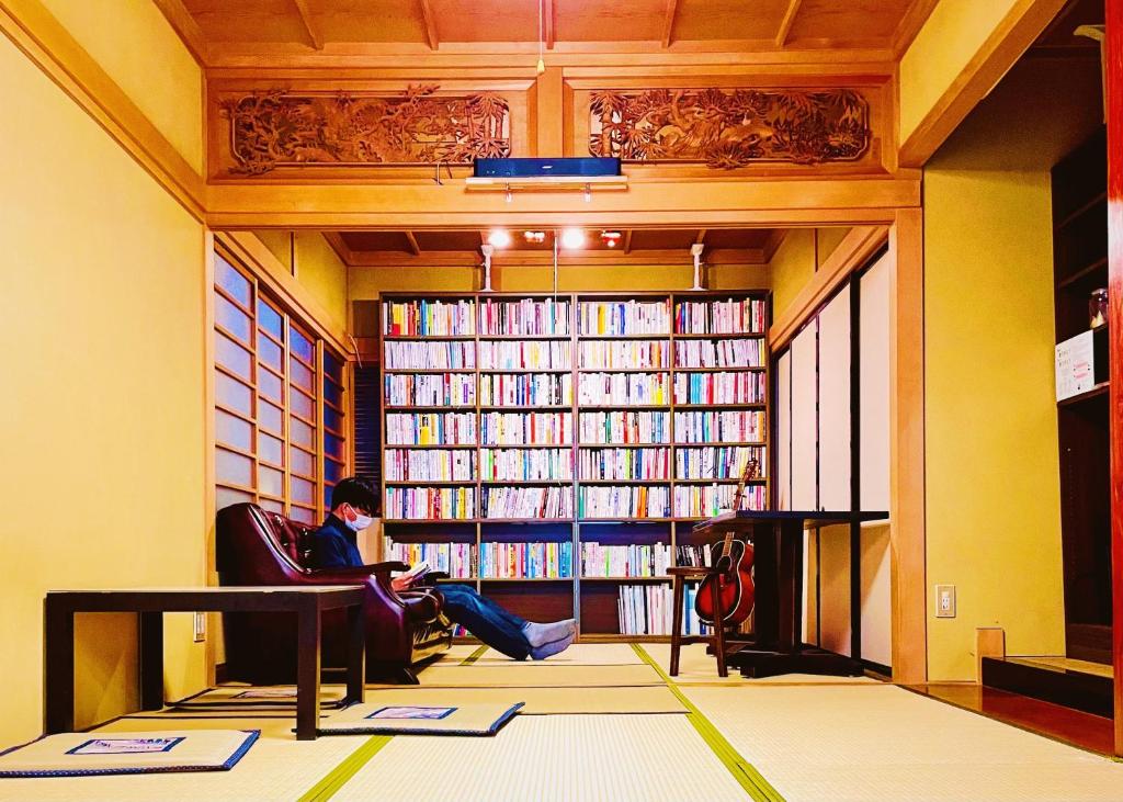 富山市にある泊まれる図書館 寄処 -yosuga-の図書館前の椅子に座る女性