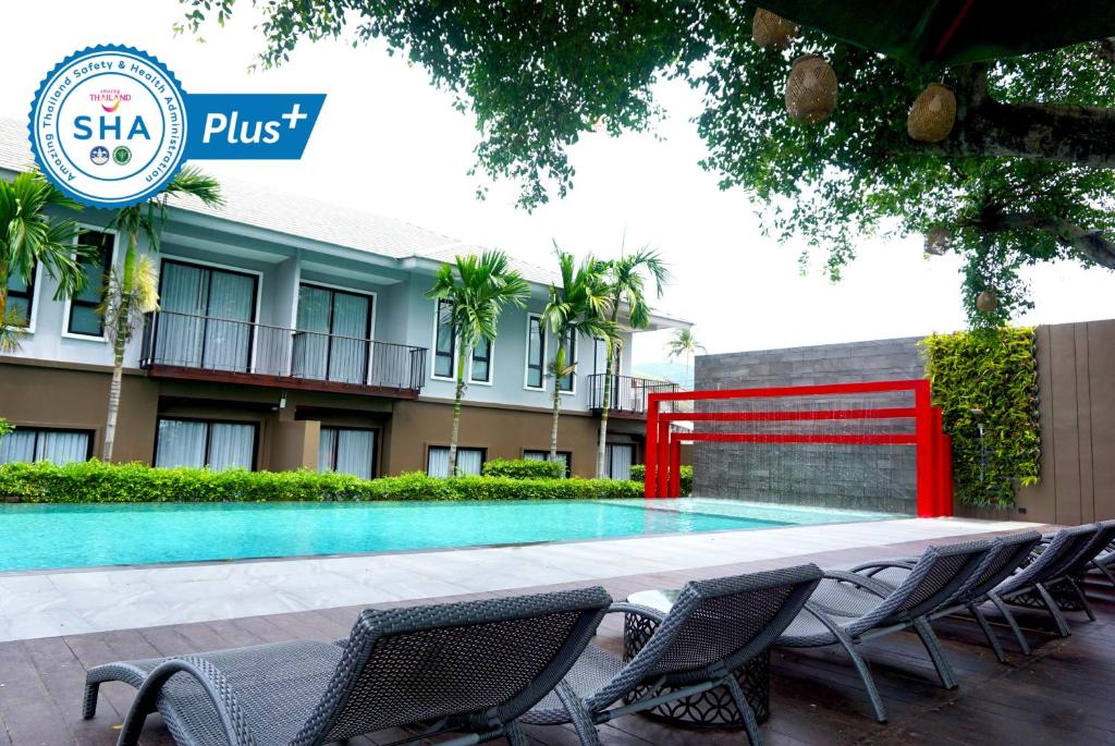 a swimming pool in front of a building with chairs at The Lake Chalong Hotel SHA Plus in Chalong 