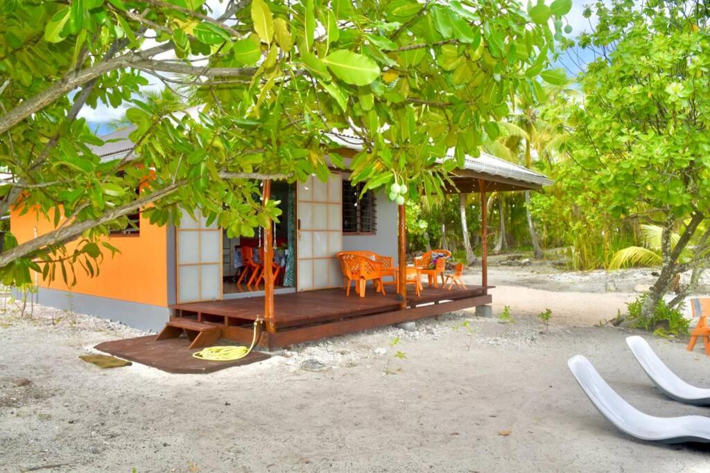 uma pequena casa com um alpendre e cadeiras em frente em Hiti Tikehau, the ocean side bungalow em Tikehau