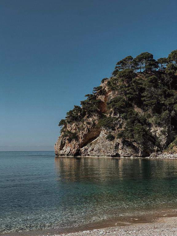 a rocky island in the water next to a beach at Casa Costa Suites in Kanali