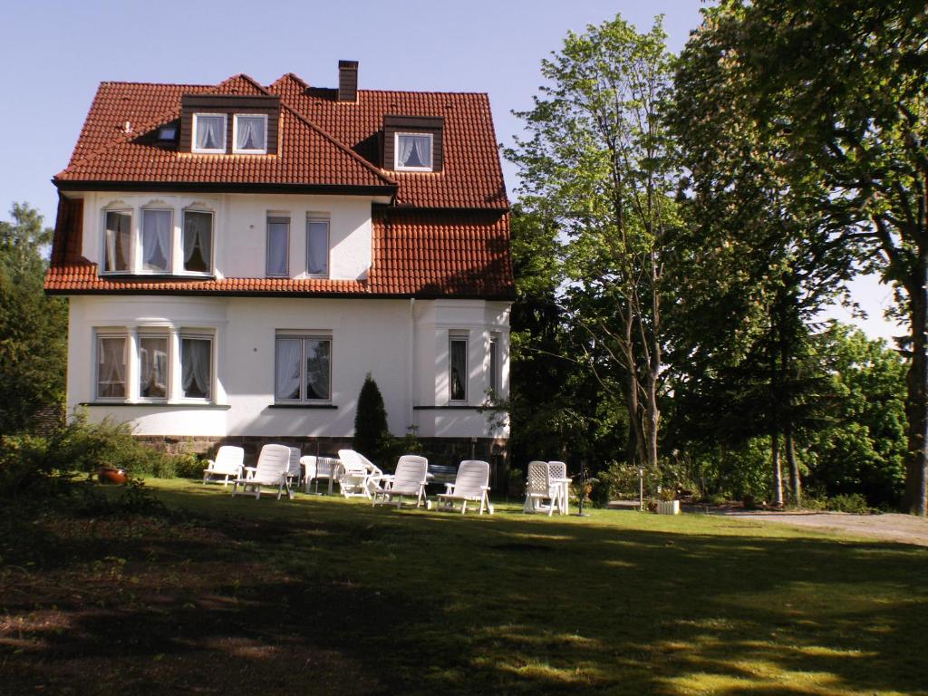 Thermen Hotel Pension Villa Holstein في باد سالزوفلين: أمامه بيت أبيض وكراسي بيضاء