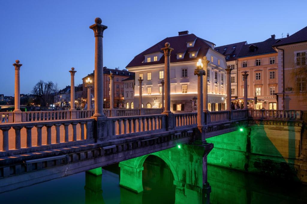 a bridge over a river in a city at night at Zlata Ladjica Boutique Hotel in Ljubljana