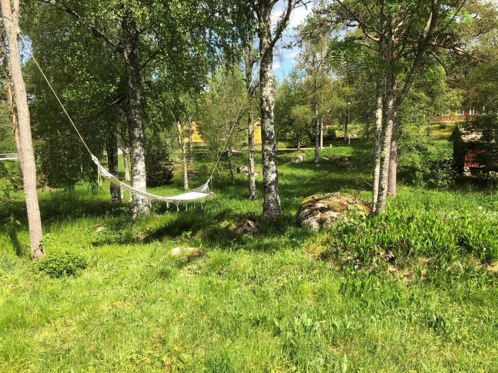 a hammock in the middle of a field with trees at Dala Cottage in Ulriksberg