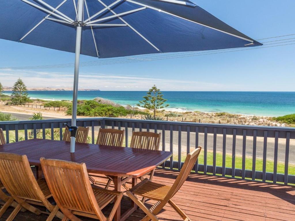 a wooden table and chairs on a deck with an umbrella at Sandy Feet 31 Gold Coast Drive in Normanville