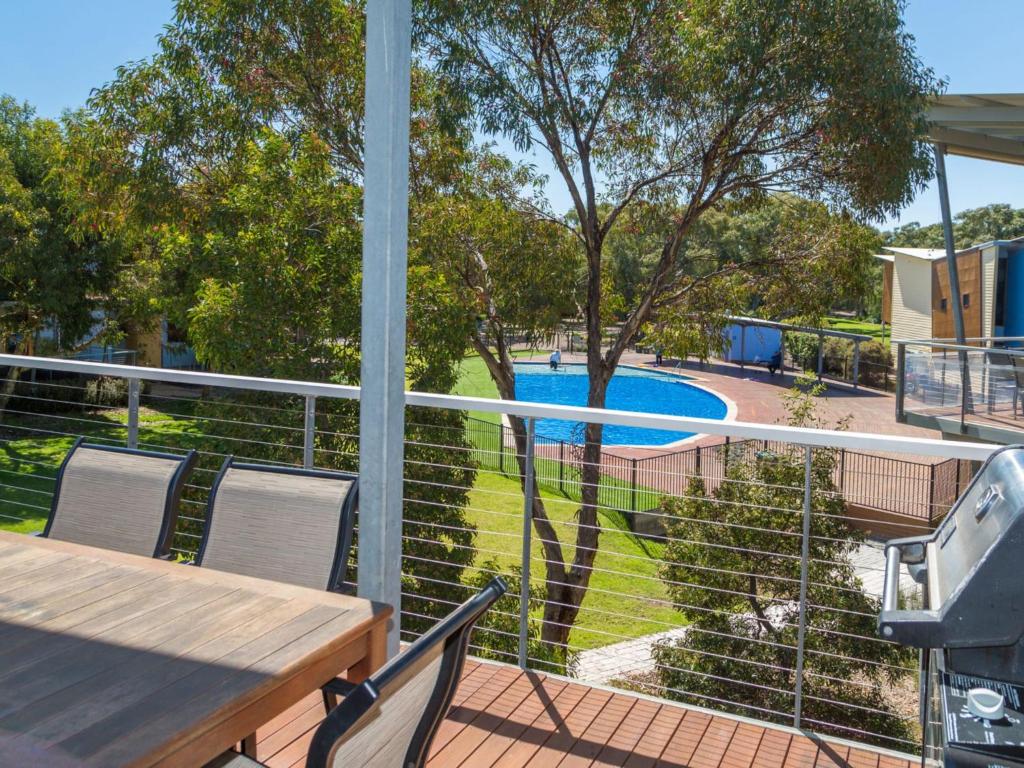 a balcony with a table and chairs and a swimming pool at South Shores Villa 52 in Normanville