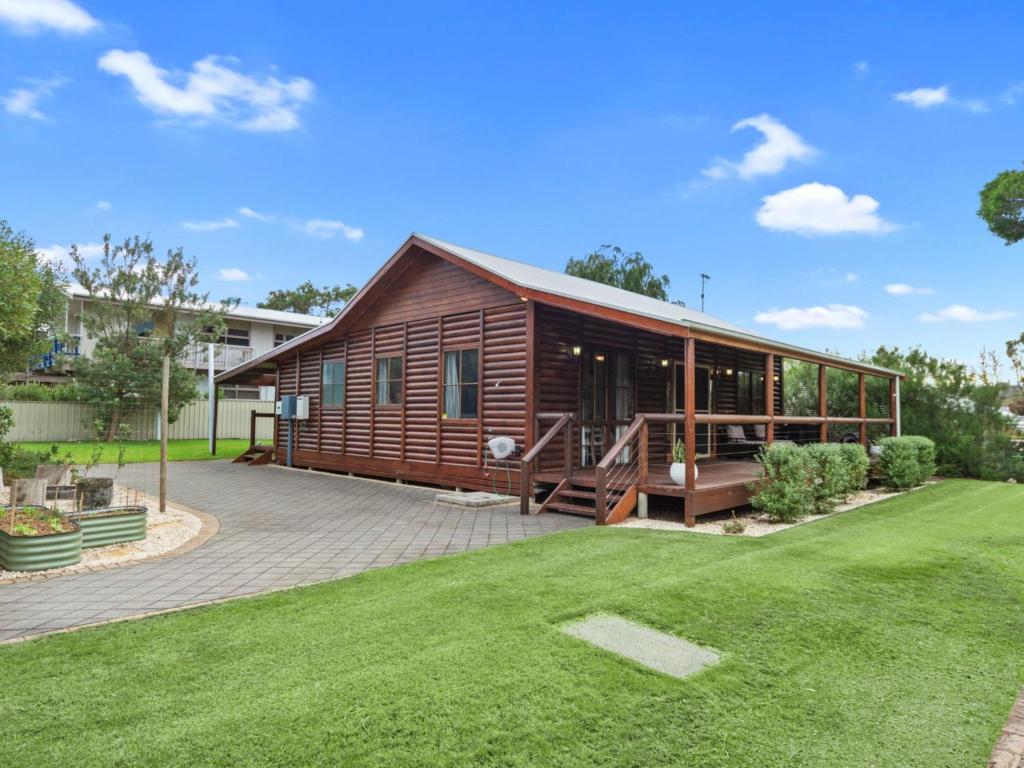 a log cabin with a deck and a lawn at 47 Jetty Road in Normanville