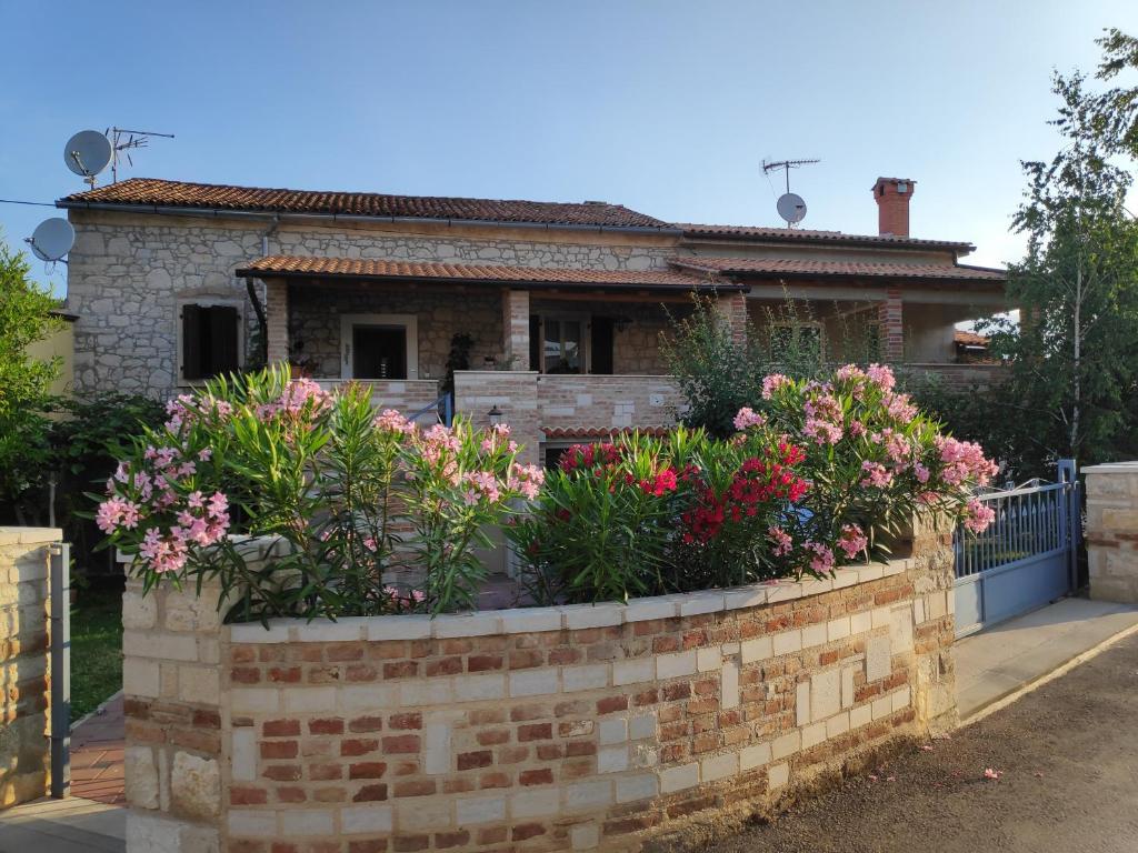 una pared de ladrillo con flores frente a una casa en Apartmani Memić 100 m do plaže, APARTMENTS MEMIĆ ONLY 100M FROM BEACH, en Poreč