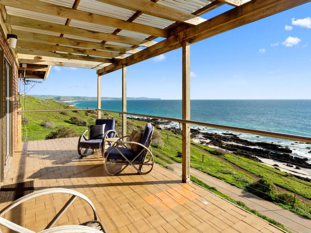 um alpendre com duas cadeiras e vista para o oceano em Cliffs End Beach Shack 105 Gold Coast Drive em Carrickalinga