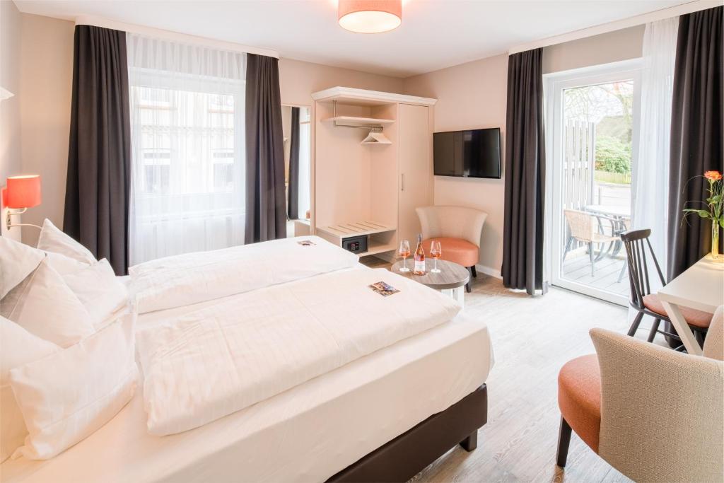 Habitación de hotel con cama grande y sala de estar. en Flair Hotel Rieckmann en Bispingen