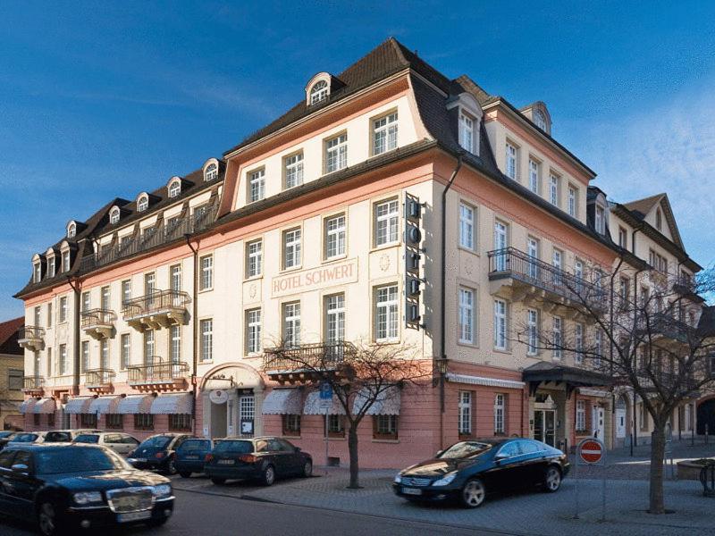 un gran edificio con coches estacionados frente a él en Hotel Schwert en Rastatt