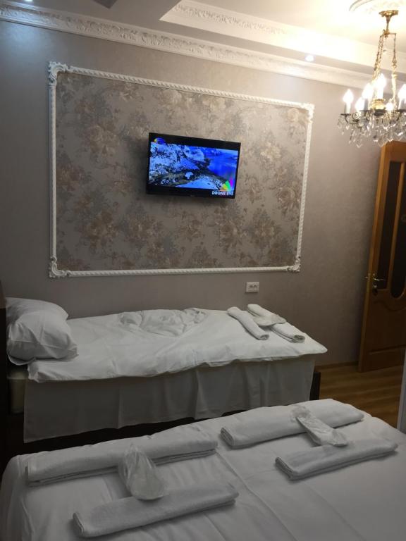 a room with two beds and a tv on the wall at HOTEL COMFORT in Kutaisi