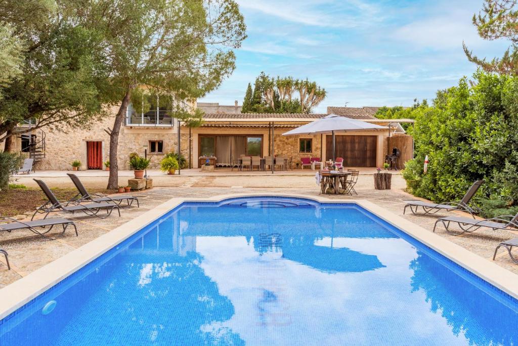 a pool with chairs and a table and a house at Finca Son Palanca in Sineu