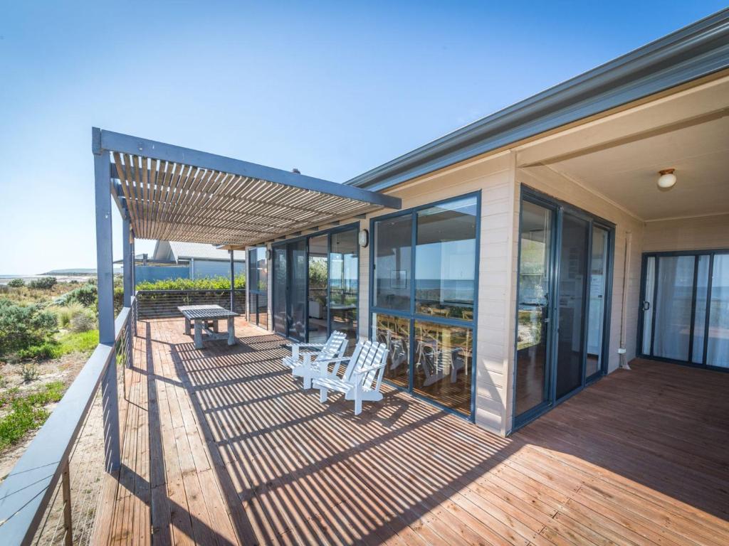 a house with a deck with a table and chairs at 20 Lady Bay Road in Normanville