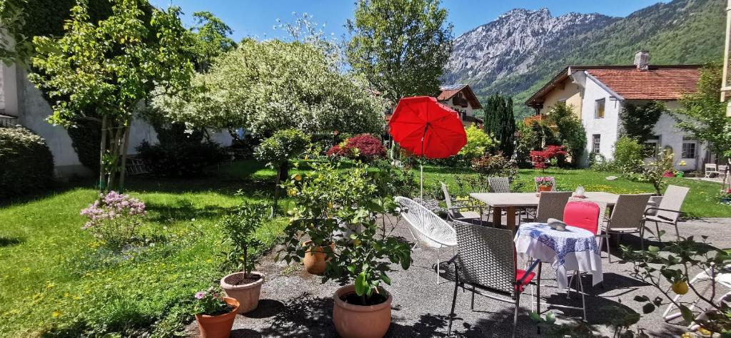 un patio con una mesa y una sombrilla roja en Villa Rosen - Ferienwohnungen, en Bad Reichenhall
