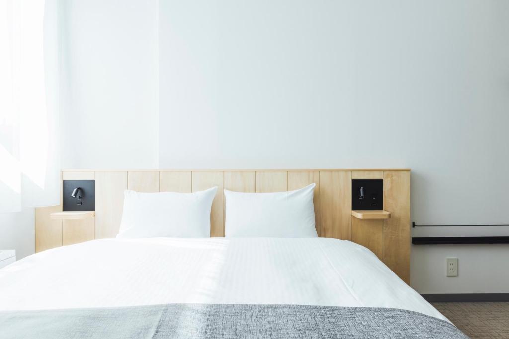 a bedroom with a white bed with two pillows at Hotel Nupka in Obihiro