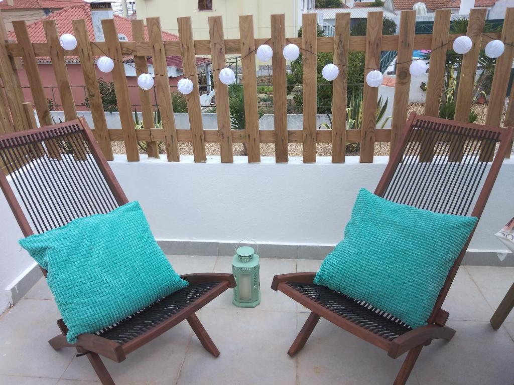 2 chaises avec des oreillers bleus assises sur une terrasse dans l'établissement Angel's House, à Quinta do Anjo