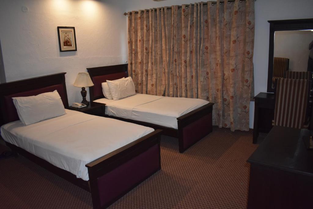 um quarto de hotel com duas camas e uma janela em Elysium 99 em Islamabad