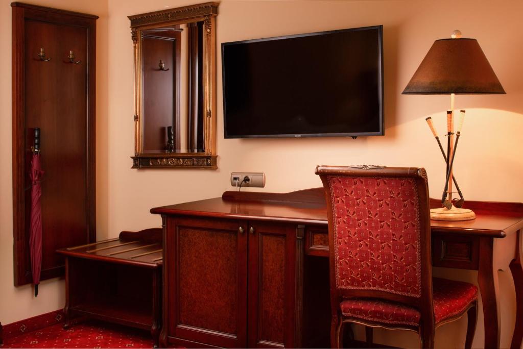 カルロヴィ・ヴァリにあるアクア マリーナのデスク、テレビ、椅子が備わるホテルルームです。