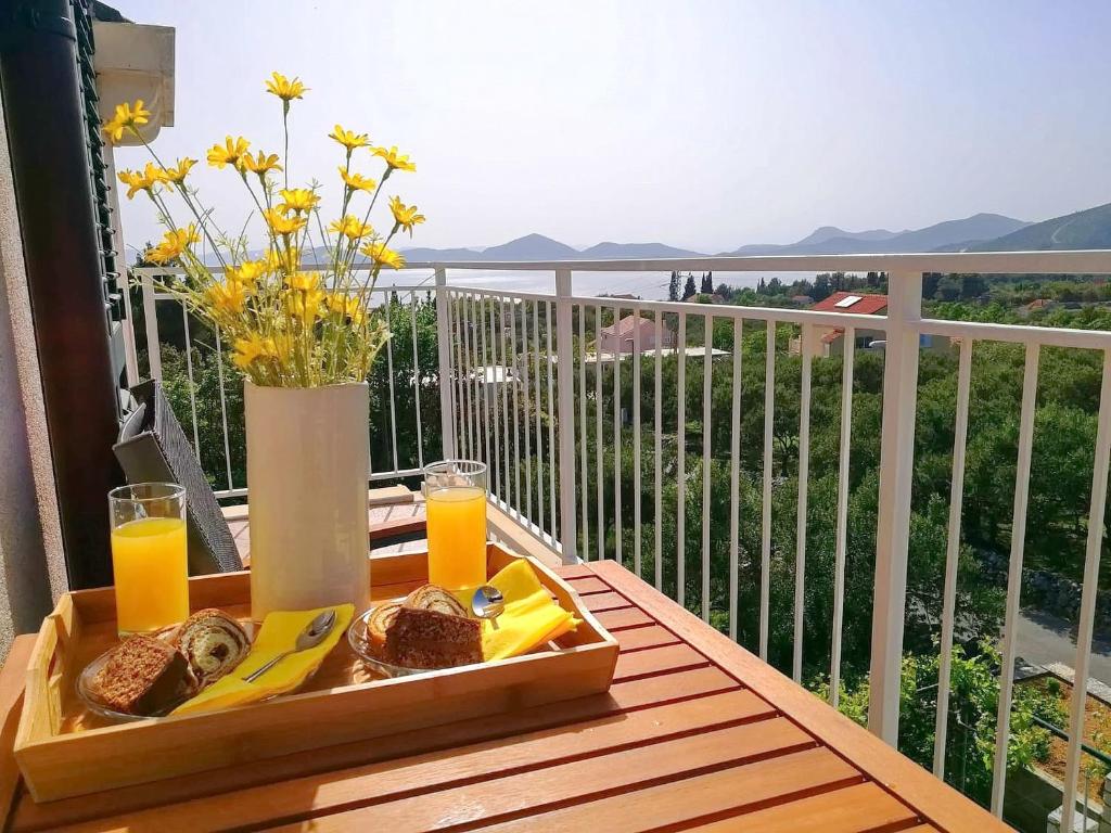 ein Tablett mit Brot und Orangensaft auf einem Tisch auf einem Balkon in der Unterkunft Apartments Kola in Banići