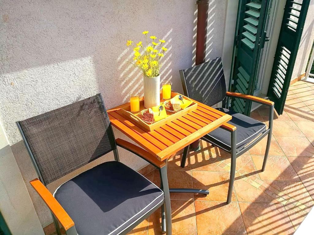 een tafel en stoelen op een patio met bloemen erop bij Apartments Kola in Banići