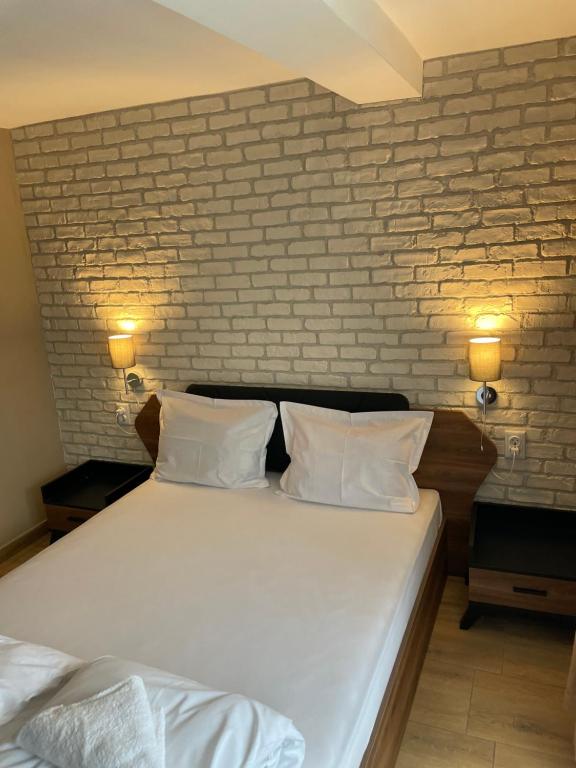 a bedroom with a white bed with a brick wall at Family Hotel Malibu in Chernomorets