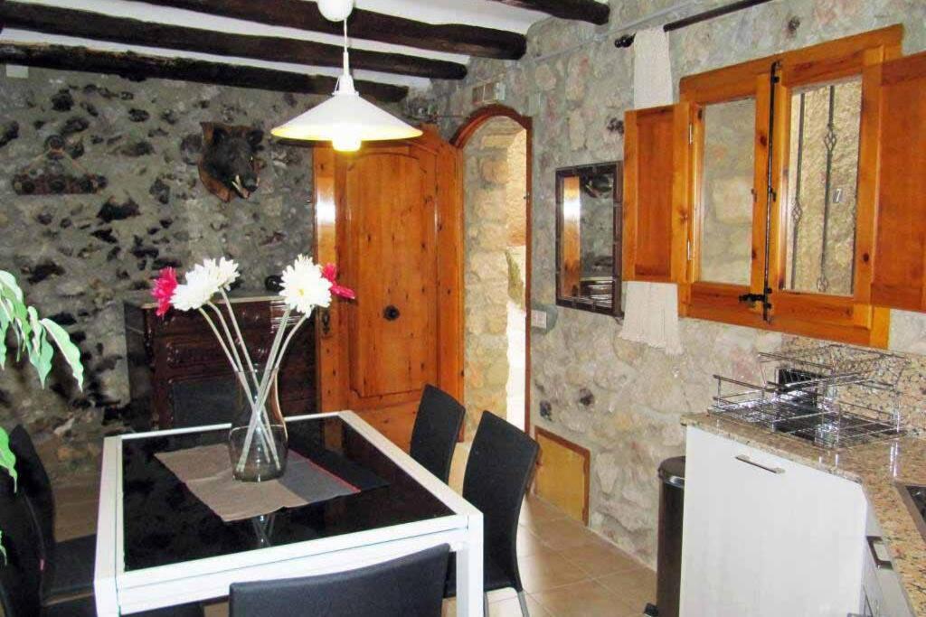 Guesthouse "La Gloria de Arbolí" في Arboli: مطبخ مع طاولة عليها إناء من الزهور