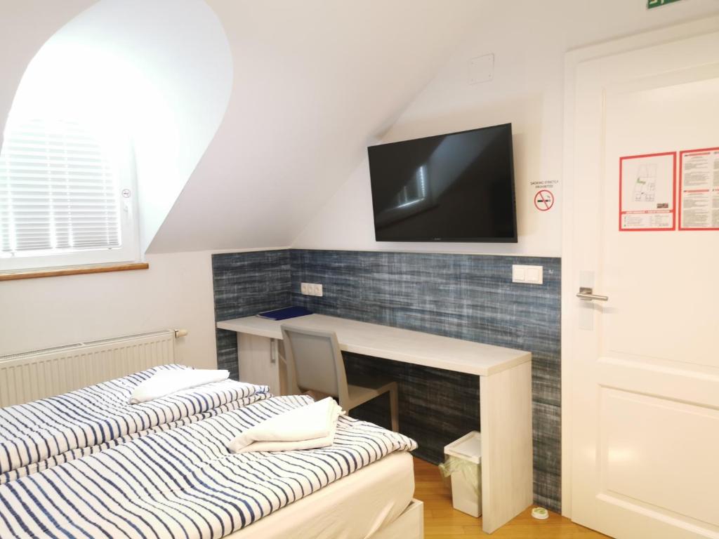 Habitación con escritorio y TV en la pared. en H2O Hostel, en Liubliana