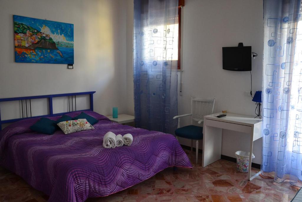 una camera da letto con un letto viola e due asciugamani di A Due Passi da Erice B&B a Erice