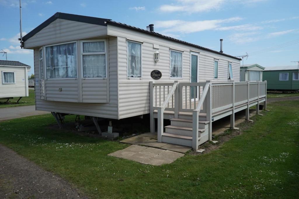 a small white house with a porch on the grass at Lyntons 3 bedroom caravan pets stay free in Heacham