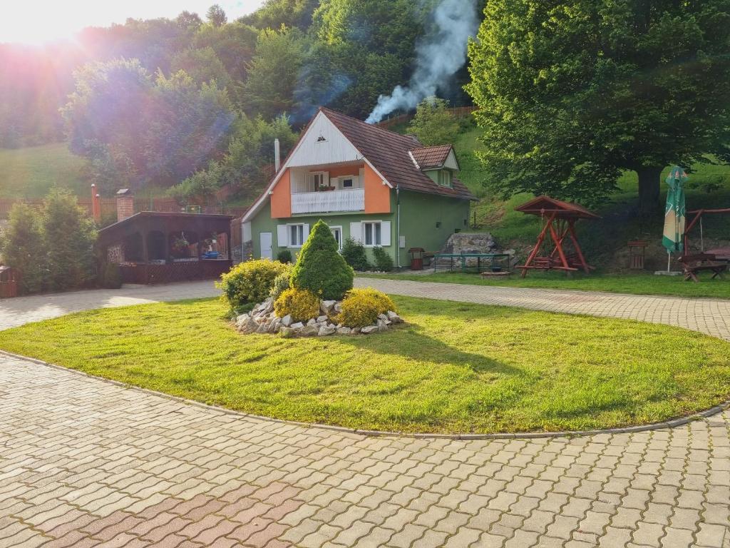 une maison sur un cercle d'herbe devant une maison dans l'établissement Silentium Clavem Domus II., à Satu Mare