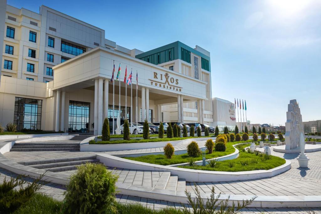 un grand bâtiment avec drapeaux devant lui dans l'établissement Rixos Turkistan, à Türkistan