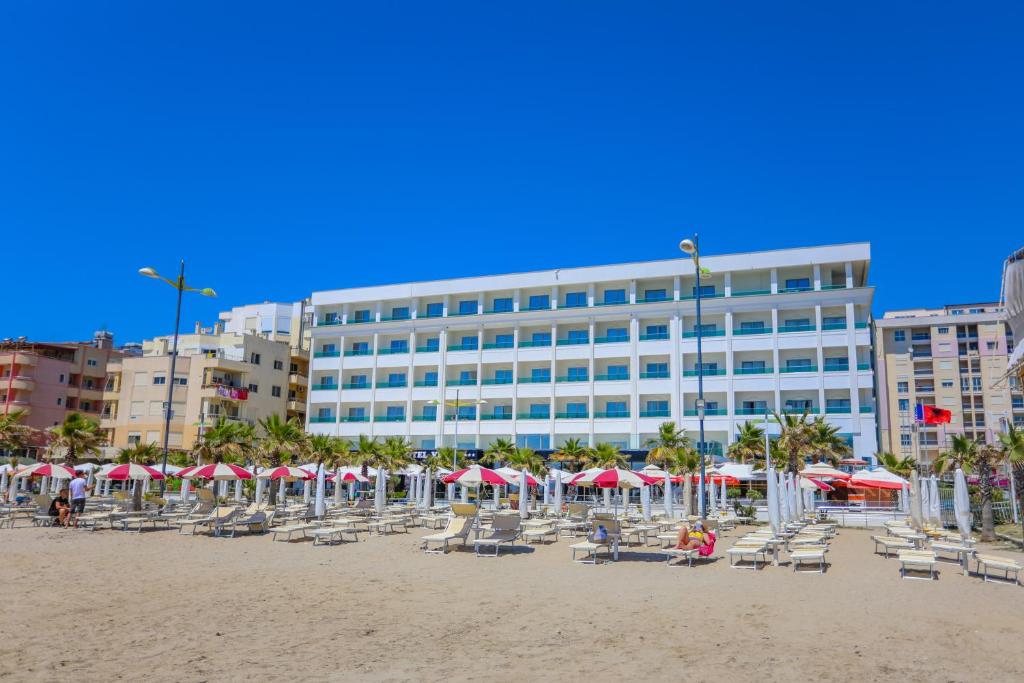 a beach with chairs and umbrellas and a building at Hotel Vivas in Durrës