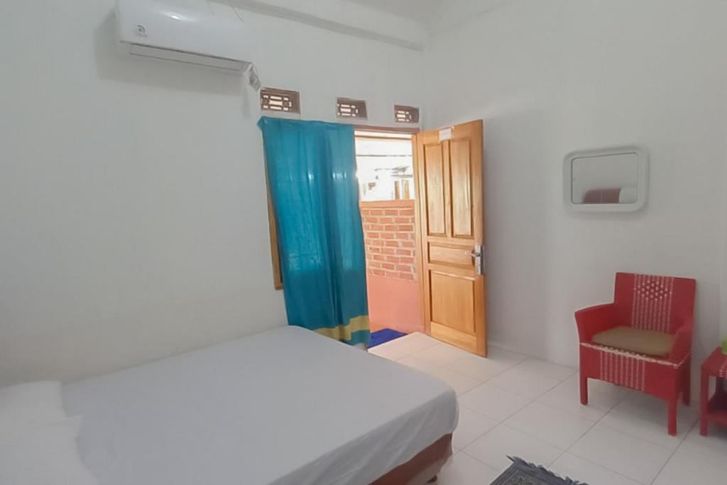 um quarto com uma cama, uma cadeira e uma porta em AA BUNGSU Syariah Balekambang Ciletuh Sukabumi RedPartner em Cilowa
