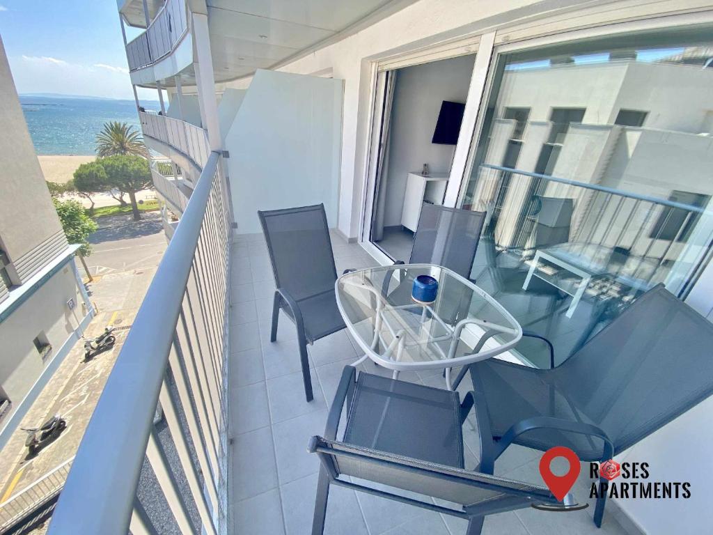 een balkon met een glazen tafel en stoelen bij Roses Apartments Ocean 2 habitaciones vista mar lateral in Roses