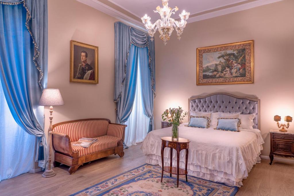 a bedroom with a bed and a chair and a chandelier at Palazzo Cavagna Sangiuliani in Bereguardo
