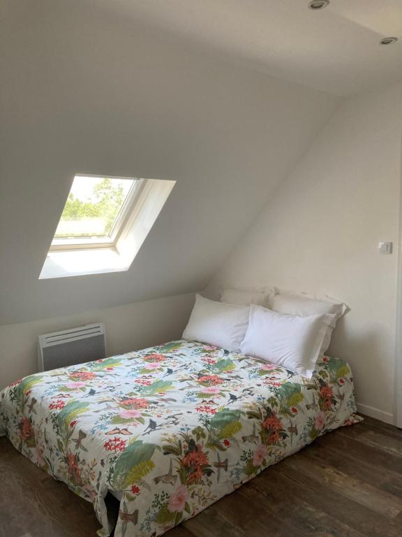 a bedroom with a bed with a floral comforter and a window at Le chemin de la Loire in Amboise