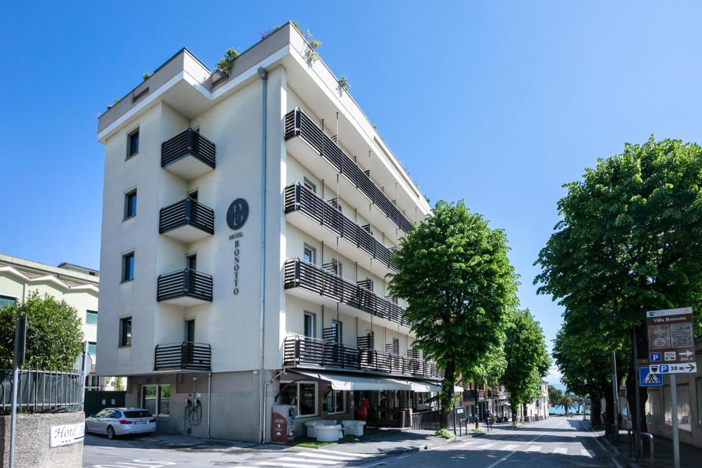 a white building with balconies on a street at Hotel Bonotto in Desenzano del Garda