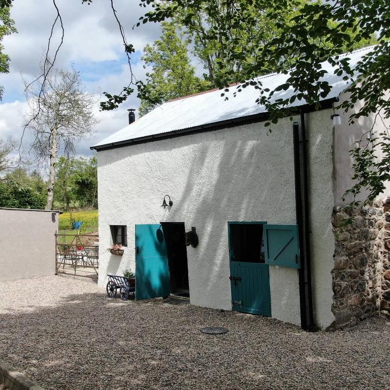 a white building with green doors and a fence at Blackshaw's Studio in Scolboa
