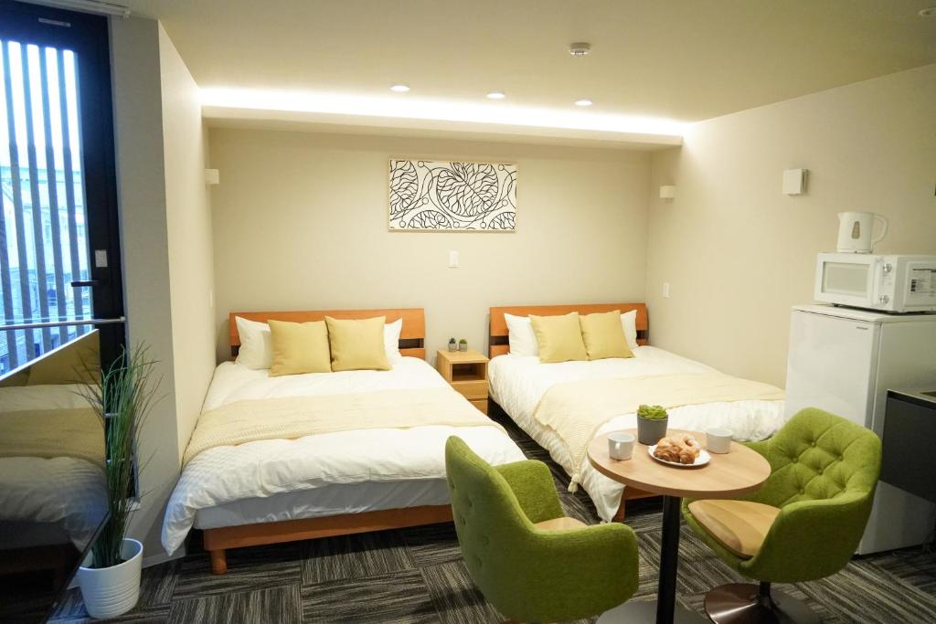 大阪市にあるKoti Sopo Universal Bay 3 by Liaisonのベッド2台、テーブル、椅子が備わる客室です。