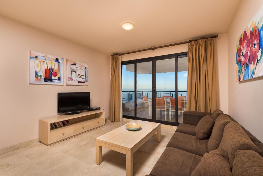 een woonkamer met een bank en een tv bij Exclusivo apartamento 2 dormitorios in Torrox Costa